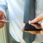 business man entering data of a credit card . On-line shopping on the internet using a mobile phone